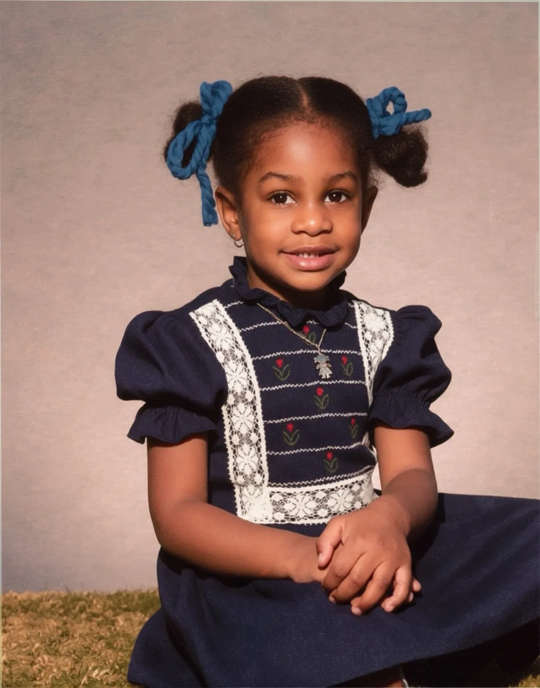 Childhood portrait of Kathryn Finney, around age four, in a navy dress with lace collar, hands folded in her lap